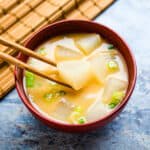 Daikon miso soup being scooped up with a chopstick.