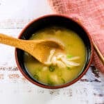 Shimeji miso soup being scooped up with a spoon.