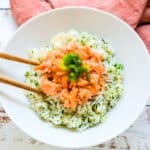 Japanese salmon rice bowl being scooped with chopsticks.