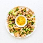 Yuzu pepper chicken served on a plate topped with green onions.