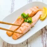 Toaster oven baked salmon strips being picked up with chopsticks.