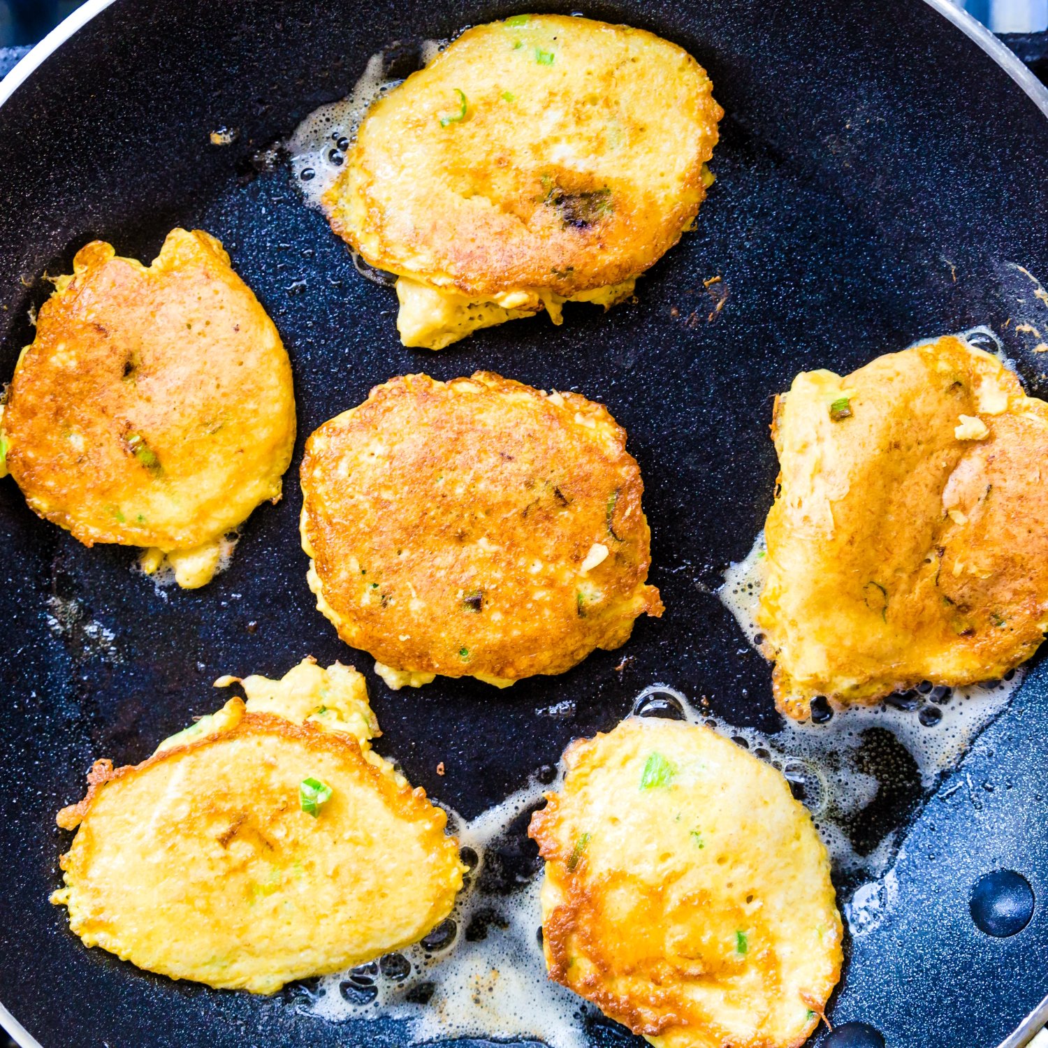 Crab cake is cooked in a frying pan. 