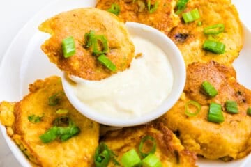 Crab cake being dipped into lemon garlic aioli.