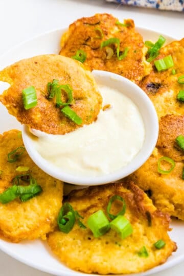 Crab cake being dipped into lemon garlic aioli.