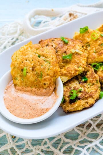 Crab cakes being dipped into Old Bay aioli dipping sauce.