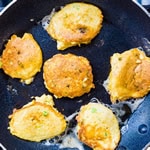 Crab cakes being cooked in a frying pan.