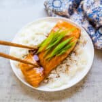 Pan fried glazed teriyaki salmon being picked up with a chopstick.