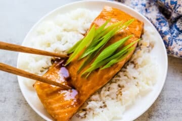 Pan fried glazed teriyaki salmon being picked up with a chopstick.