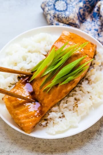 Pan fried glazed teriyaki salmon being picked up with a chopstick.