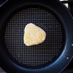 Rice ball being seared in a frying pan.