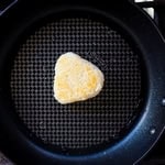 Rice ball being seared in a frying pan.