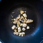 Cubed chicken being cooked in a wok.