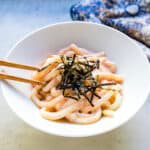 Tarako udon being picked up with a pair of chopsticks.