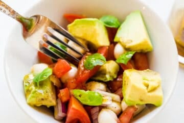 Avocado mozzarella salad being picked up with a fork.