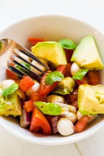 Avocado mozzarella salad being picked up with a fork.