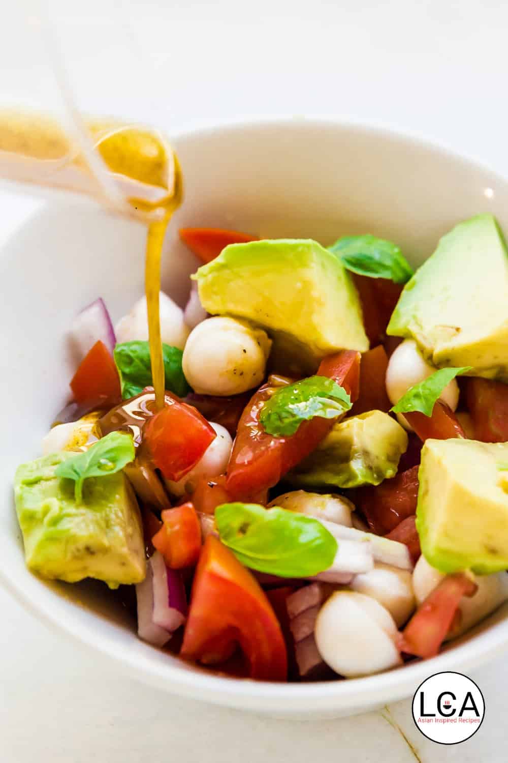 Pour the dressing over the avocado mozzarella salad.