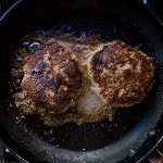 Japanese style hamburger patty being cooked in a frying pan.