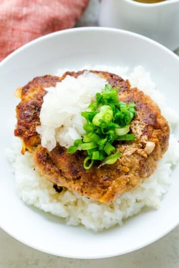 Japanese hamburger served on top of rice in a bowl drizzled in Japanese wafu sauce and topped with green onions.