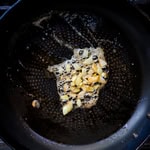 Diced onions being browned in a frying pan.