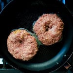 Japanese hamburger patty being cooked in a frying pan.