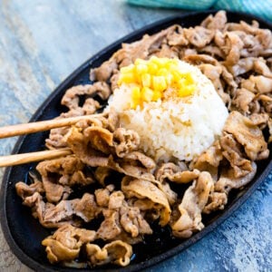 Pepper lunch pork is being picked up with a pair of chopsticks.