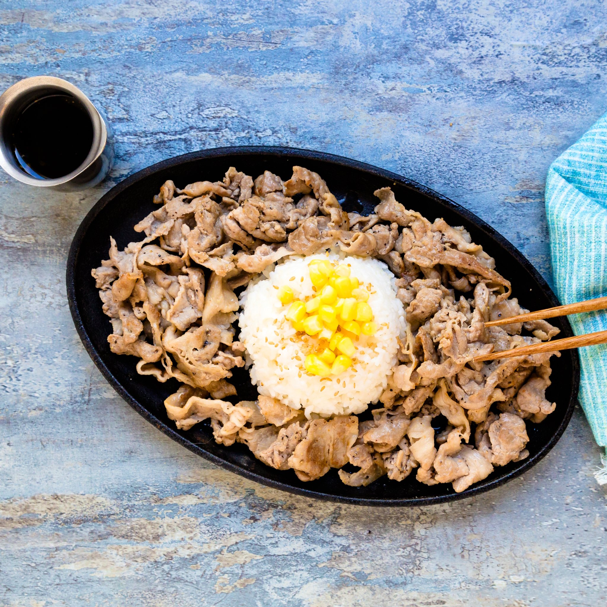 Pepper lunch pork is being picked up with a pair of chopsticks.