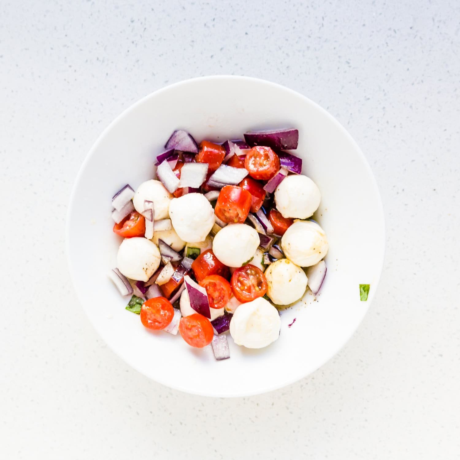 Place chopped tomatoes, red onion, and mozzarella cheese in a mixing bowl.